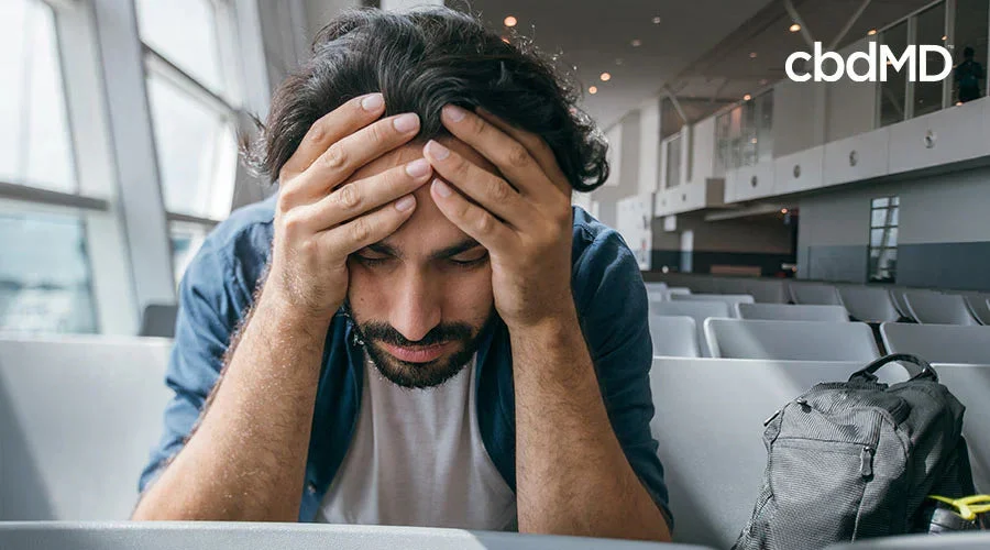 Tired man with head in hands at airport, travel fatigue, jet lag prevention concept