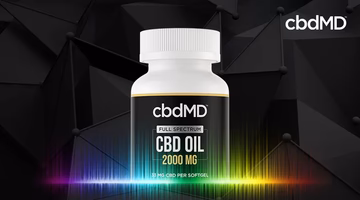 Full spectrum CBD oil bottle with 2000 MG label on black geometric background and rainbow light effect