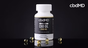 Full spectrum CBD oil softgels bottle with scattered capsules on black background