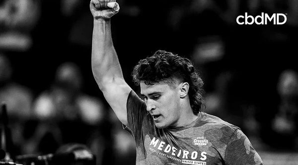 Athlete raising fist in victory, wearing CrossFit shirt, cbdMD logo visible