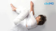 Woman sleeping on her side in a relaxed fetal position on white bedding