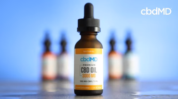 Dropper bottle of 3000mg premium CBD oil with blurred bottles on blue background