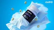 CBD sleep supplement bottle on pillows with capsules, blue sky background
