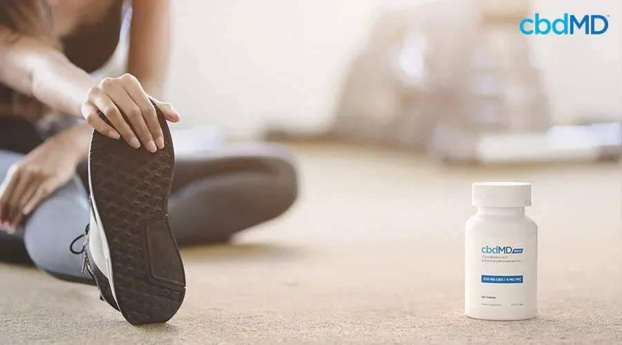 Woman stretching on floor next to CBD supplement bottle for muscle recovery