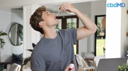 Young man taking CBD oil drops with a dropper indoors in a modern home setting