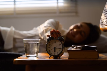 woman turning off her alarm clock on her nightstand
