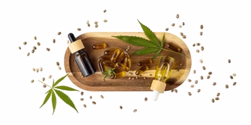 CBD tincture bottles, capsules, hemp leaves, and seeds on a wooden tray