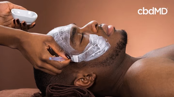 Man receiving facial treatment with aloe vera and shea butter cream applied to face