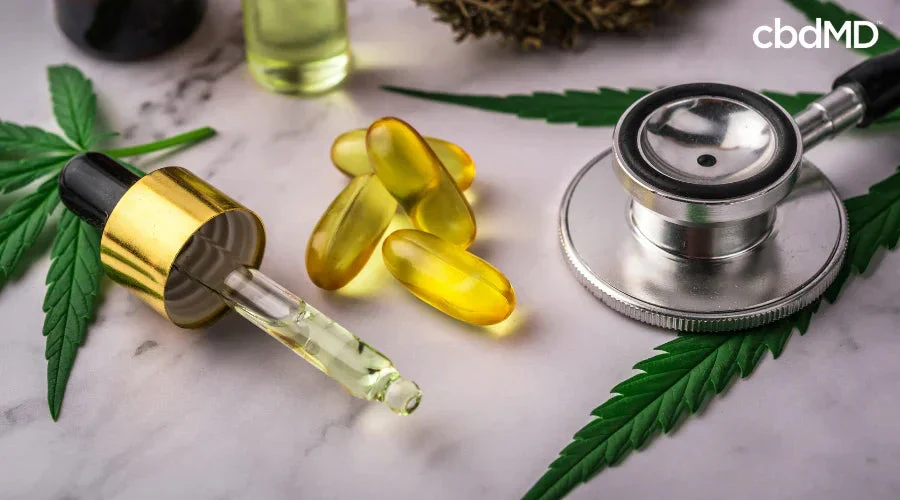 CBD oil dropper, capsules, stethoscope, and hemp leaves on a marble surface