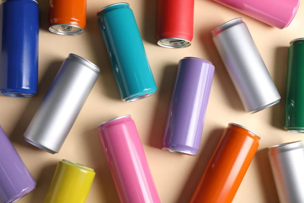 selection of colorful aluminum beverage cans on a beige background