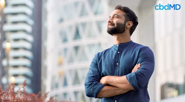 Confident, happy man standing outdoors with arms crossed, smiling in an urban setting