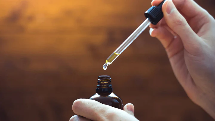 Person using dropper with CBD oil tincture for wellness routine
