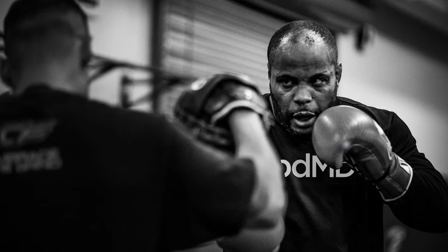 Male boxer training indoors, wearing gloves, intense focus during workout.