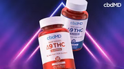 Two bottles of delta-9 THC gummies, labeled cherry and blue razz, on a purple neon background.