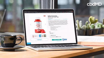 Laptop displaying Delta 9 THC gummies product page on desk with coffee cup and plants