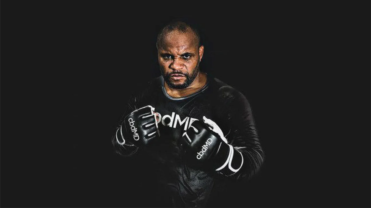 Male athlete in black mma gloves and shirt with cbdMD logo, posing in fight stance