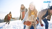 Group of friends playing in winter snow, wearing warm clothing, bright sunlight