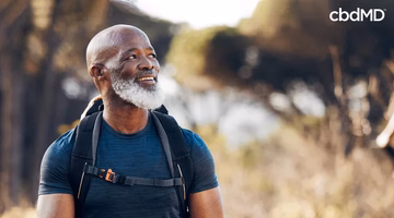 Smiling man with backpack walking outdoors in nature, enjoying healthy lifestyle