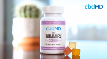 CBD gummies bottle with assorted gummy supplements on a table, labeled 300 mg tropical mix.