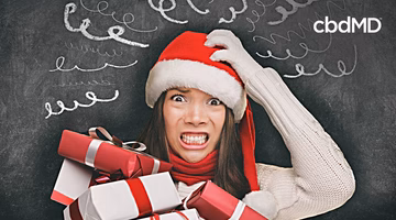 Stressed woman in Santa hat holding holiday gifts with scribbles on chalkboard background