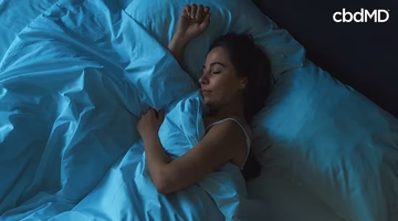 Woman peacefully sleeping in bed with blue sheets, promoting restful sleep support