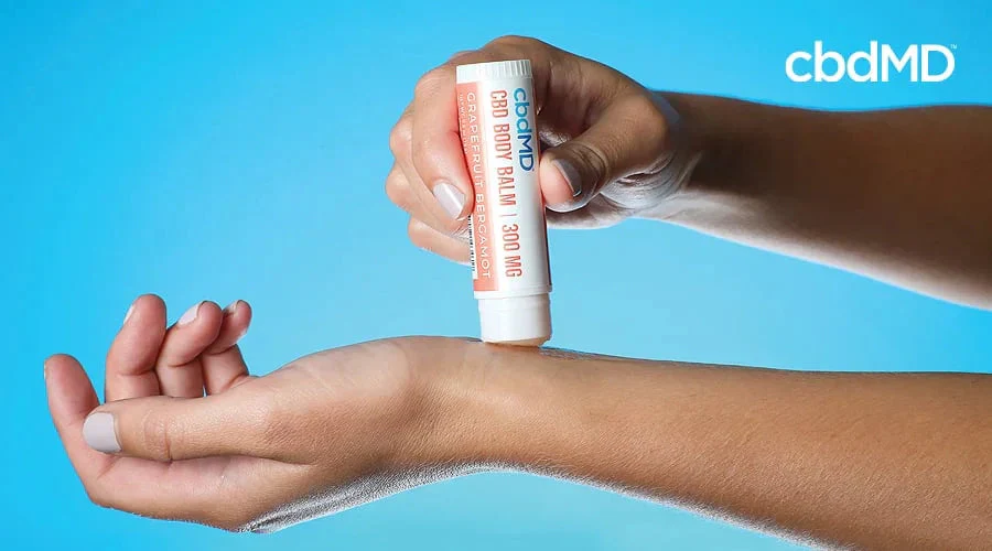 two extended arms with one hand applying a cbd topical to the inner wrist of the other arm