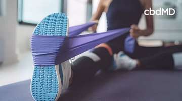 Woman stretching on yoga mat at home using resistance band for leg exercise