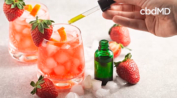 Iced strawberry drinks being infused with oil from a dropper, fresh strawberries nearby