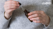 Person holding CBD oil dropper bottle, preparing dose for wellness routine