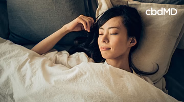 Woman peacefully sleeping in bed, promoting restful CBD wellness support