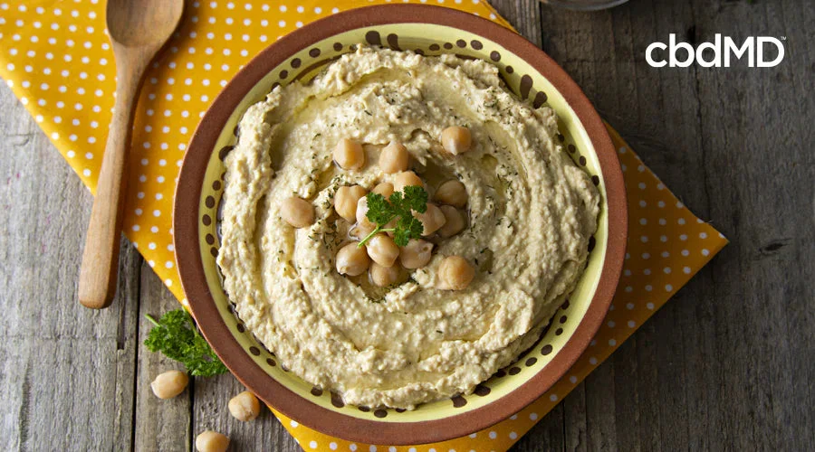 Chickpea hummus in a bowl, topped with whole chickpeas and parsley on a rustic wooden table