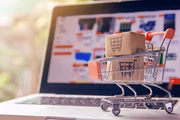 Mini shopping cart with boxes on laptop keyboard, representing online shopping and e-commerce.
