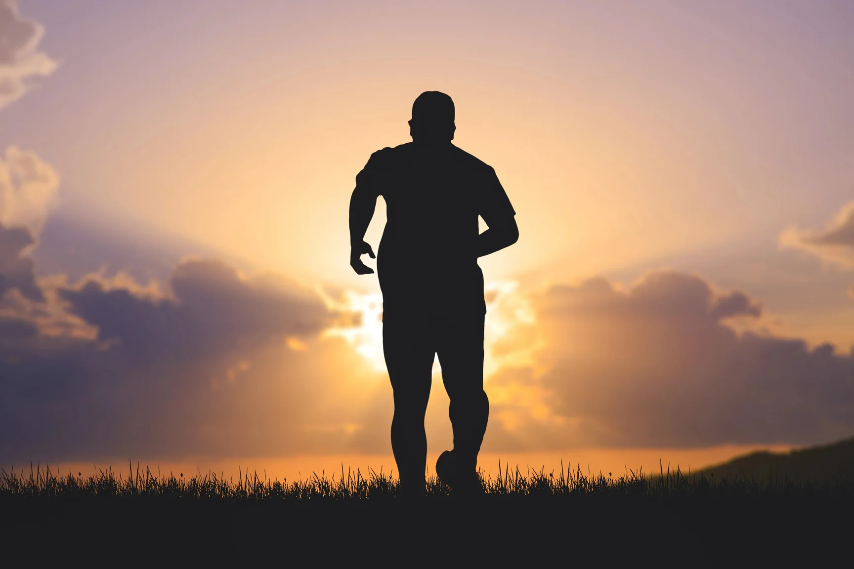 Silhouette of man running outdoors during sunset with cloudy sky background