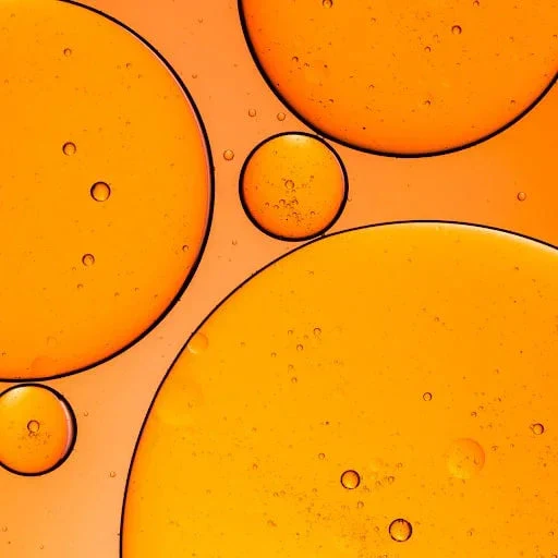 Close-up of orange oil droplets in liquid, abstract wellness and natural ingredient concept.