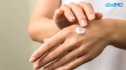 Person applying CBD pain relief cream to the back of their hand
