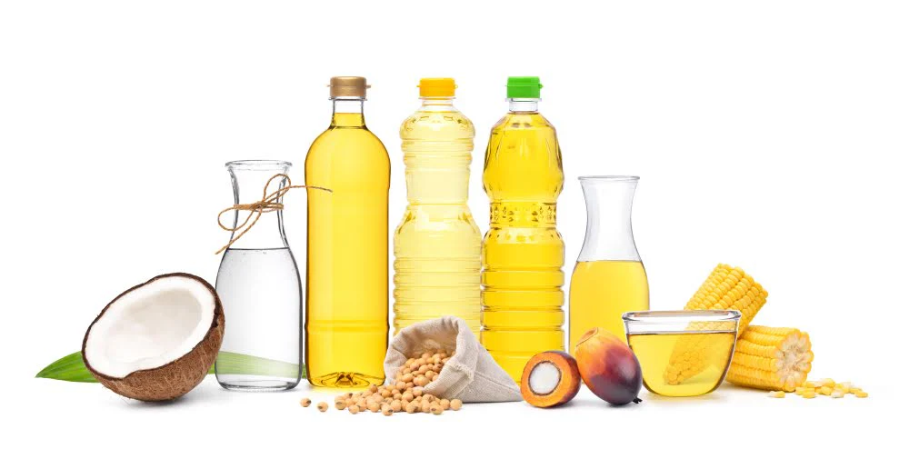 various types of oils and nuts on a white counter with a white background