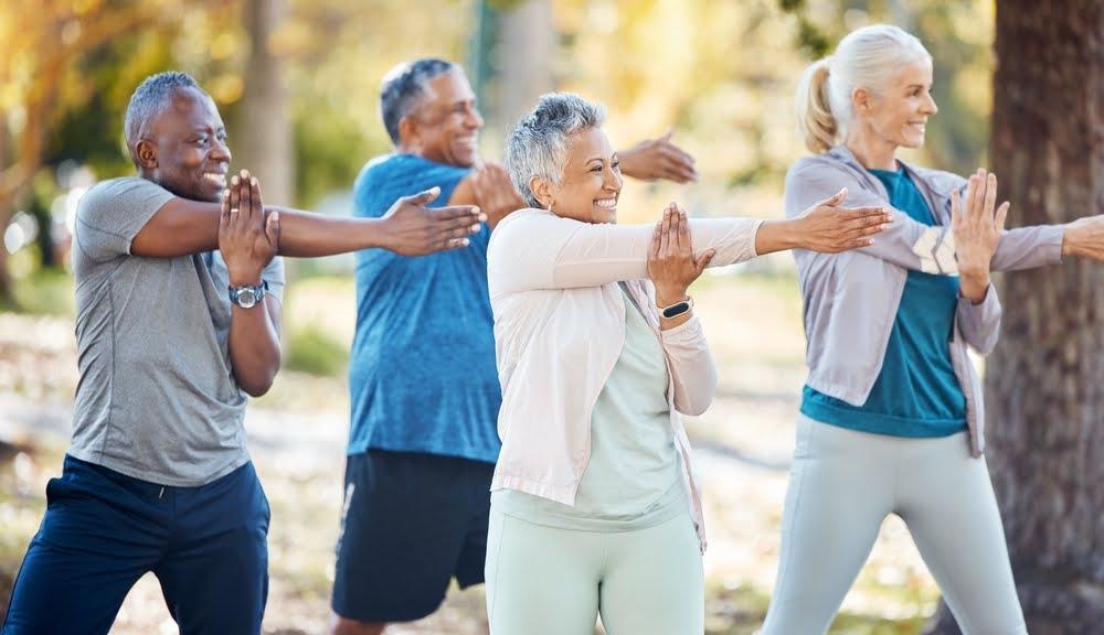 Active seniors stretching together outdoors for group exercise in a sunny park setting