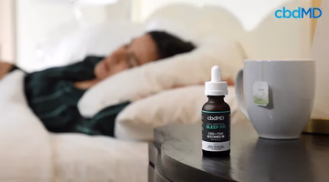 CBD PM sleep aid tincture on nightstand with tea, person sleeping in background