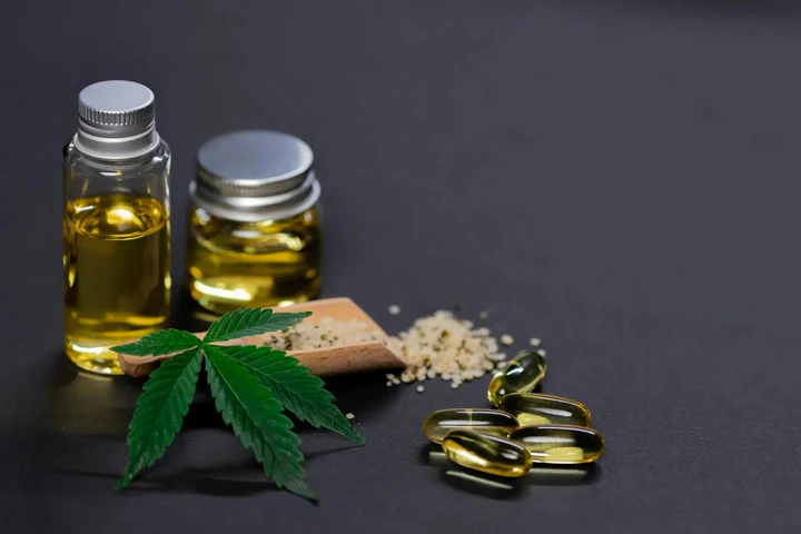 Hemp leaf, oil bottles, capsules, and seeds on black background for CBD wellness