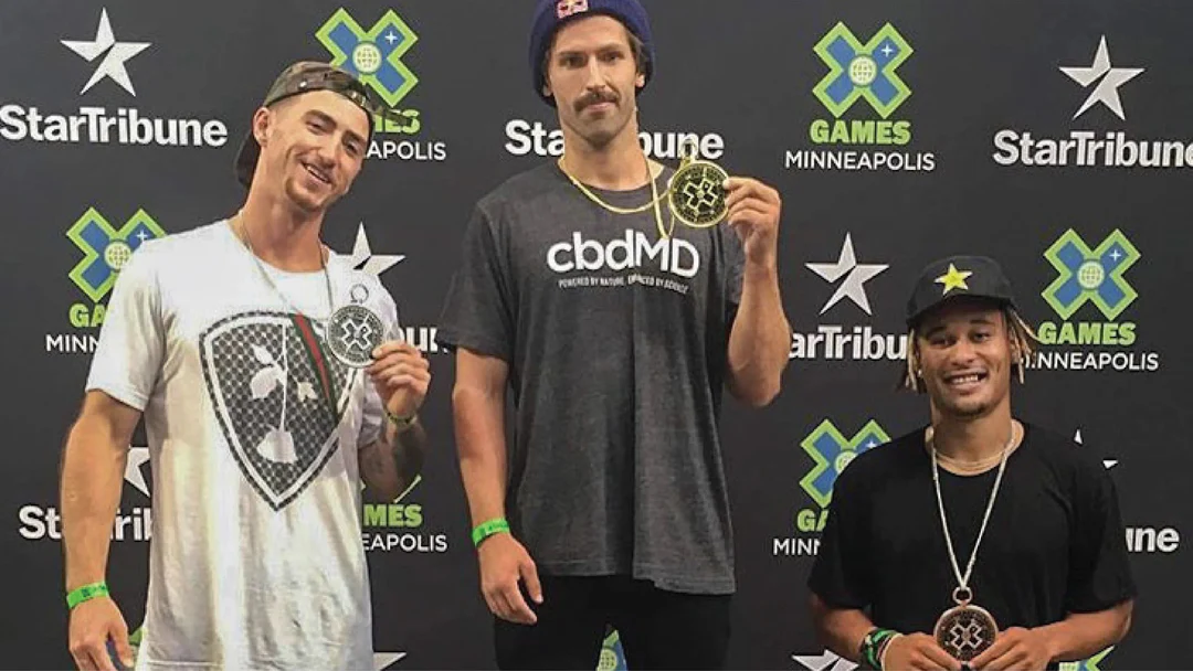Three X Games medalists on podium, one wearing cbdMD shirt, at award ceremony in Minneapolis.