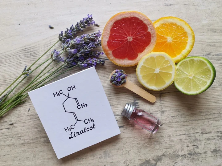 Fresh lavender, citrus fruit slices, and linalool chemical diagram on a wooden table
