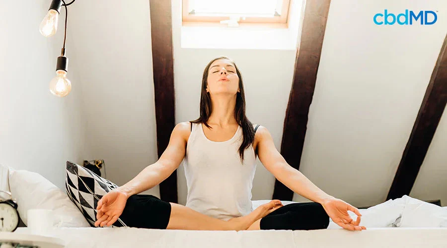 Woman practicing yoga and meditation in a bright bedroom for relaxation and focus