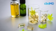 CBD oil bottles, capsules, and hemp leaves on a white surface