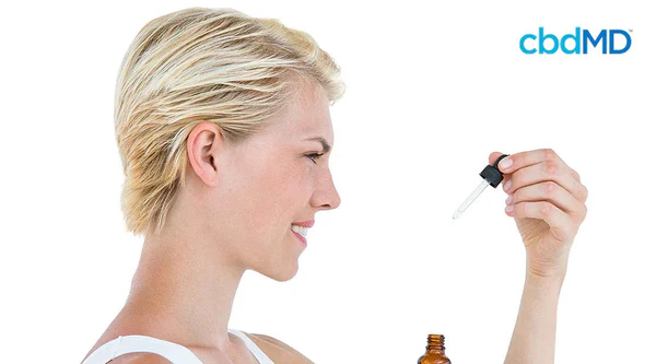 Woman holding dropper with oil next to brown bottle, health and wellness setting