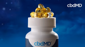 CBD softgel capsules on bottle lid with nighttime sky background