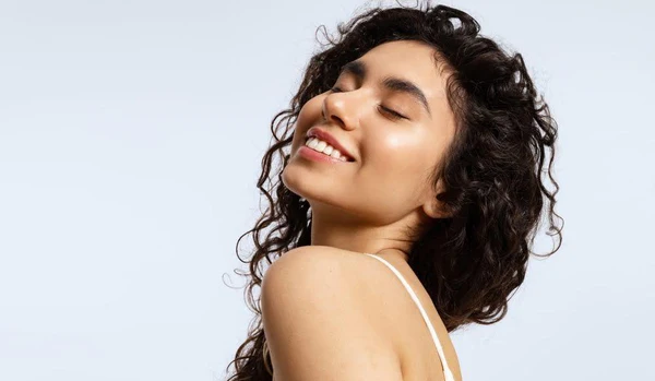 closeup of a woman smiling against a light blue backdrop