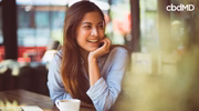 Smiling woman sitting at a table with coffee in a bright, relaxed indoor setting